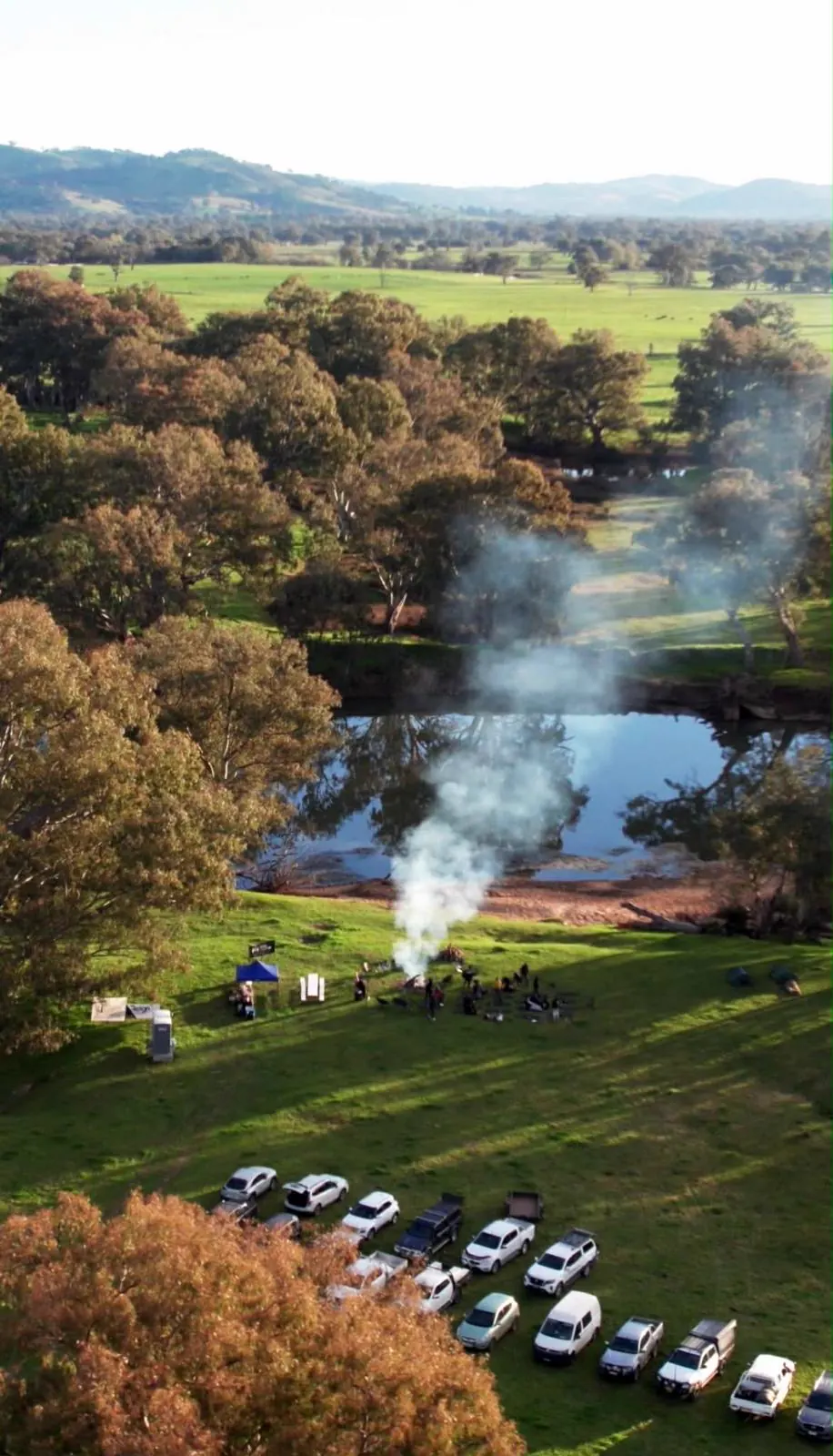 Aerial view of the retreat camp on the Murray, smoke rising from the fire and cars parked along the paddock