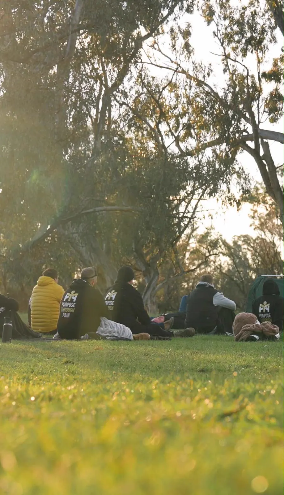 The group sitting together on the grass for the closing circle